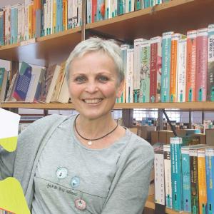 Frau in grauem T-Shirt vor Bücherregal